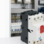 GV2-M motor protection circuit breaker in front of a control panel and a three-phase motor